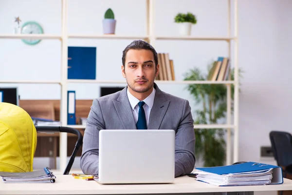 Young male employee looking after newborn at workplace