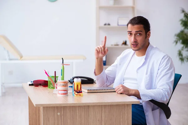 Jonge mannelijke tandarts werkzaam in de kliniek — Stockfoto