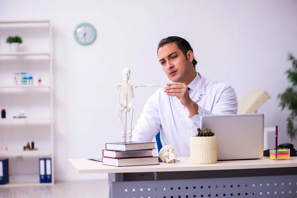 Joven médico masculino estudiando esqueleto humano — Foto de Stock