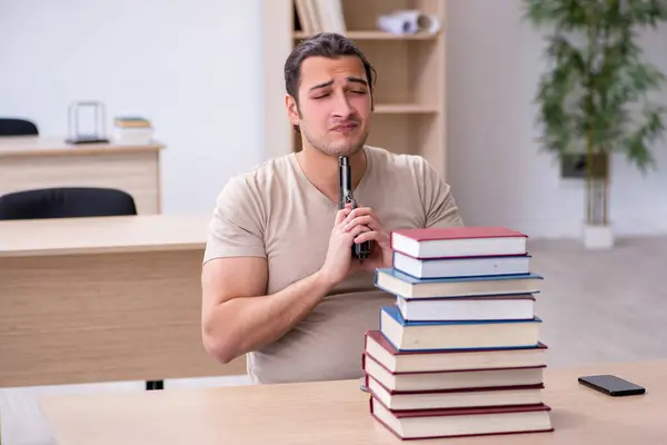 Ung mannlig student som forbereder seg til eksamen i biblioteket – stockfoto