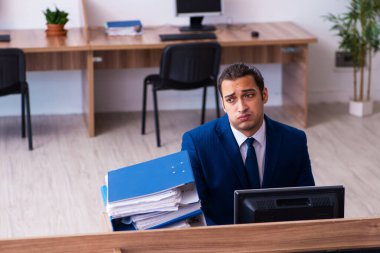 Ofisteki aşırı işten memnun olmayan genç bir erkek işçi.