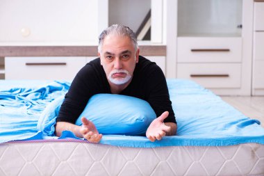 Mutsuz yaşlı adam yatak odasında.