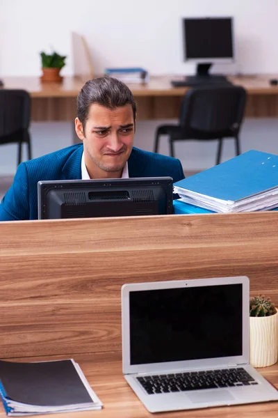 Young male employee unhappy with excessive work in the office