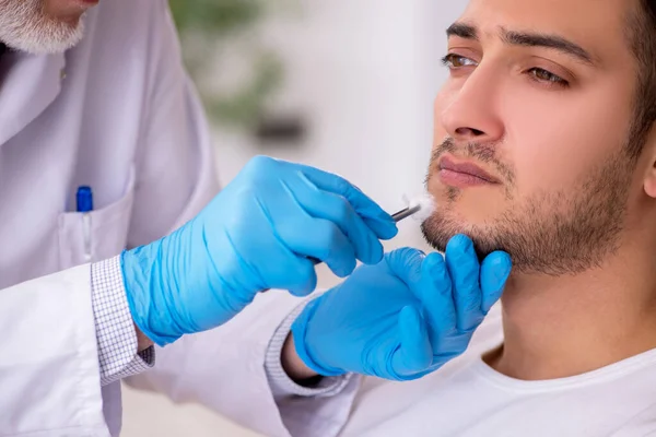 Homem jovem visitando médico dermatologista experiente — Fotografia de Stock