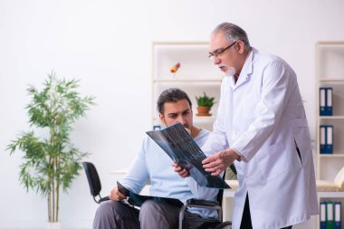 Tekerlekli sandalyedeki genç adam ve yaşlı doktor radyoloji uzmanı