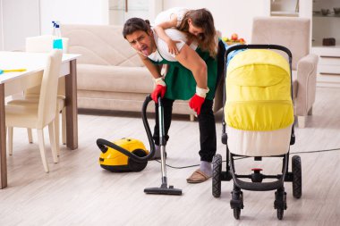 Genç erkek müteahhit, küçük kızıyla birlikte evi temizliyor.