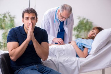 Genç koca, hasta karısını klinikte ziyaret ediyor.