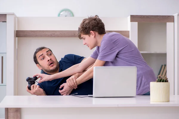 Молодой отец и школьник играют в компьютерные игры дома — стоковое фото