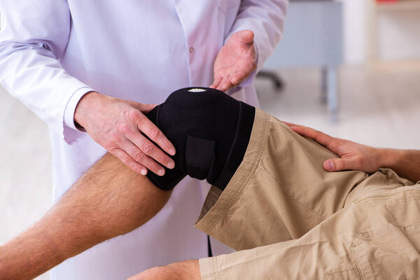 Experienced doctor traumatologist examining young male patient