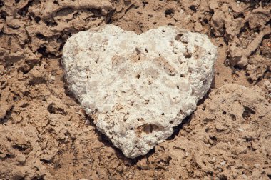 Kumda kalp şeklinde beyaz bir taş..