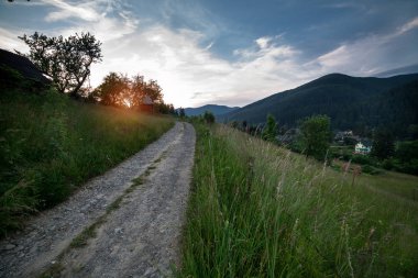 Eski köyün dağlara giden yolun Karpat Dağları'nda akşam