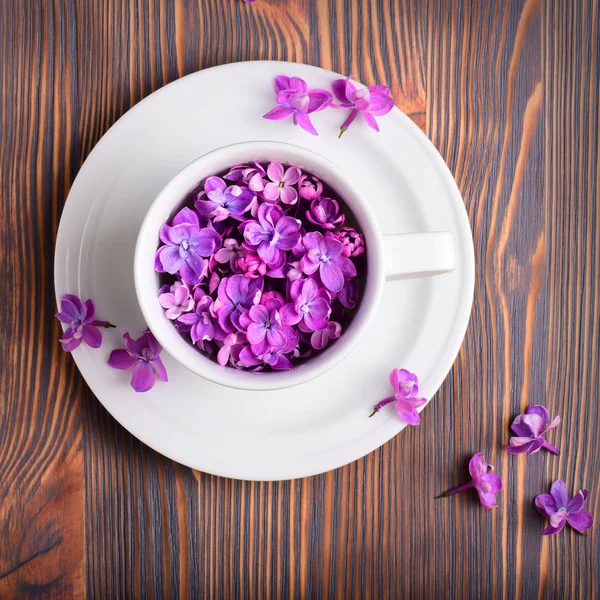 Ahşap Arka Plan Üzerinde Beyaz Çay Bardağı Tabağı Lila Çiçek — Stok fotoğraf