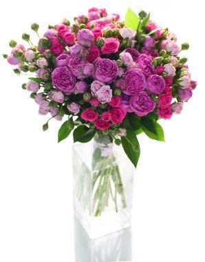 Cam vazoda beyaz arka plan üzerinde izole küçük parlak pembe ve mor gül buketi