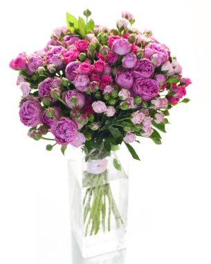 Cam vazoda beyaz arka plan üzerinde izole küçük parlak pembe ve mor gül buketi