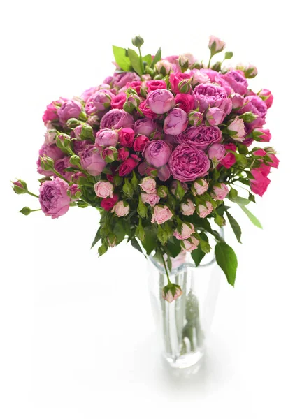 Beyaz arka plan üzerinde izole cam vazoda pembe ve mor gül buketi