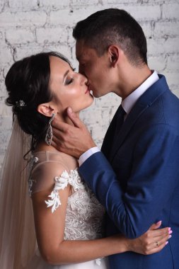 Şefkatle dokunmaktan ve tuğla duvar arka plan üzerinde gelin öpüşme damat portresi