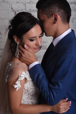 Şefkatle dokunmaktan ve tuğla duvar arka plan üzerinde gelin öpüşme damat portresi