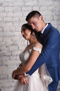 Sarılma tuğla duvar arka plan üzerinde yeni evliler portresi