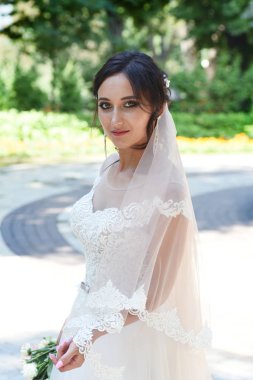 Genç esmer gelin buketi parkta poz ile