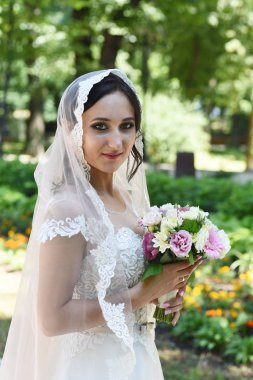 Genç esmer gelin buketi parkta poz ile