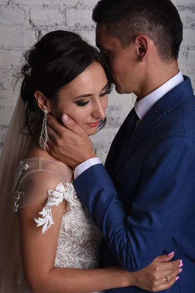 Şefkatle dokunmaktan ve tuğla duvar arka plan üzerinde gelin öpüşme damat portresi