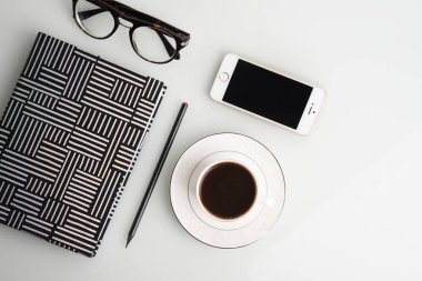Kahve fincanı, kalem, smartphone, gözlük ve çizgili Not defteri ile ofis masası