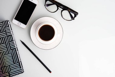 Kahve fincanı, kalem, smartphone, gözlük ve çizgili Not defteri ile ofis masası