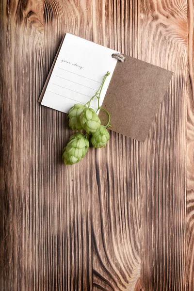 小さなメモ帳でコピー スペースを木製の背景に緑の新鮮なホップ コーン — ストック写真