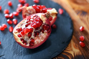 Ahşap masa üzerinde siyah taş plaka üzerinde olgun nar iki yarısı 