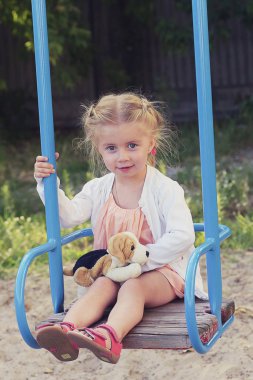 Oyun alanında sallanan örgüler ile sevimli sarışın gülümseyen kız Portresi