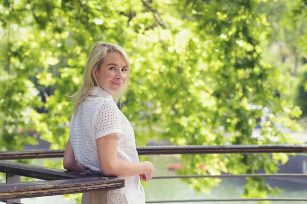 Pretty woman in white romper posing in summer park