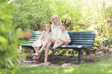 Parkta bankta birlikte oturan çocuklu anne