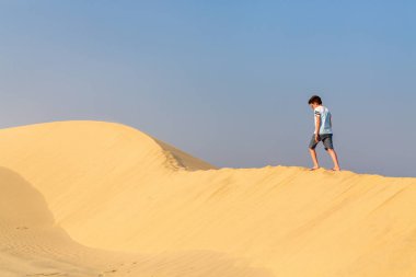 Genç çocuk eğleniyor Katar çöl kumulları oynayan