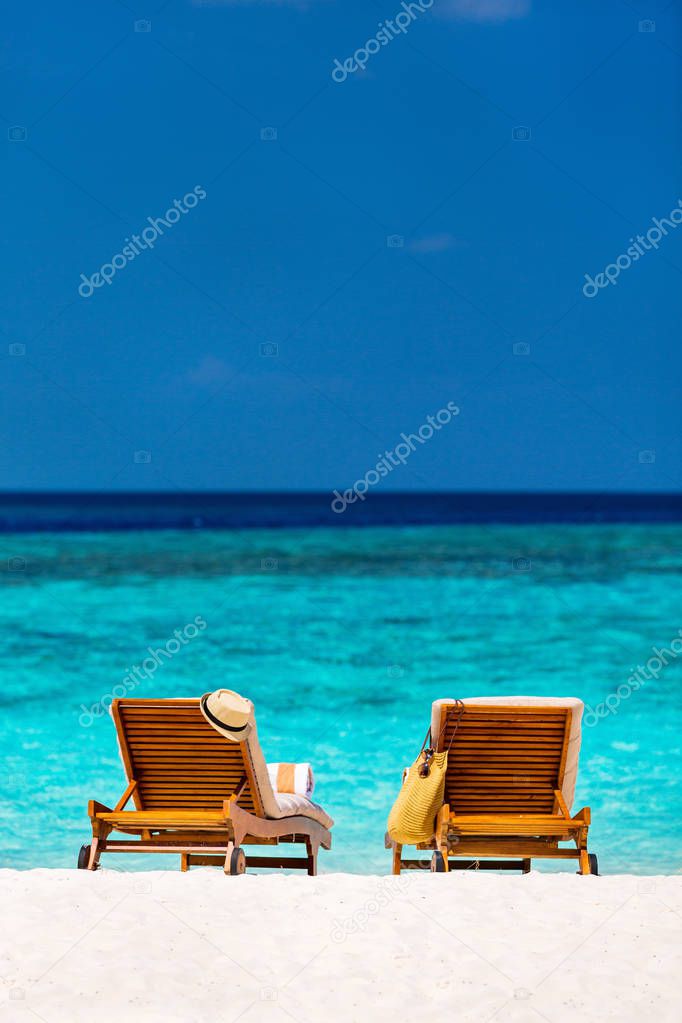 Wooden lounge chairs on a beautiful tropical beach at Maldives