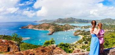 Panorama of family mother and daughter enjoying aerial view of picturesque English Harbour at Antigua and Barbuda in Caribbean clipart