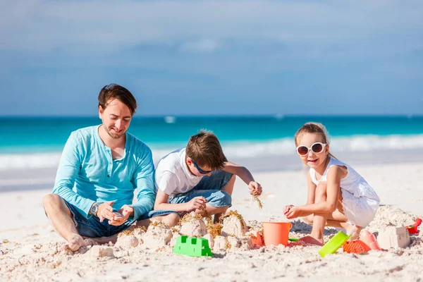 父亲和孩子们玩沙滩上的沙子 而享受暑假 — 图库照片