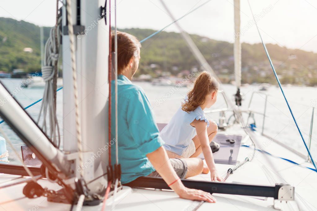 Family of father and daughter on board of sailing yacht enjoying sunset
