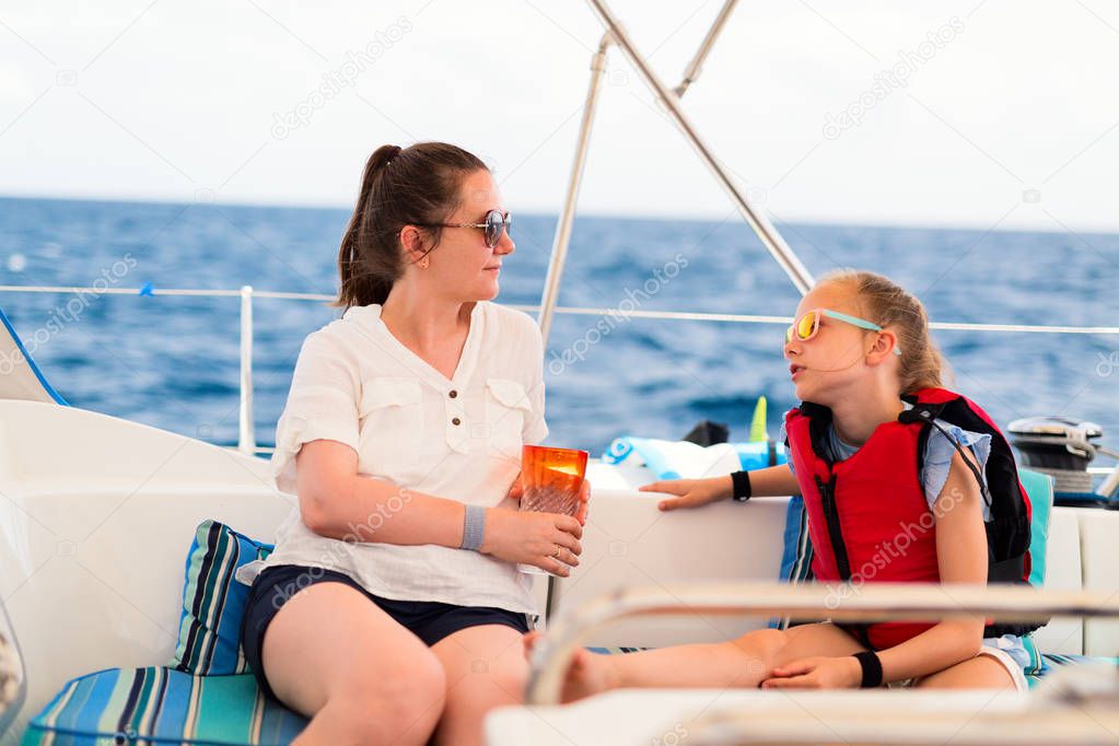 Family of mother and daughter on board of sailing yacht having summer travel adventure