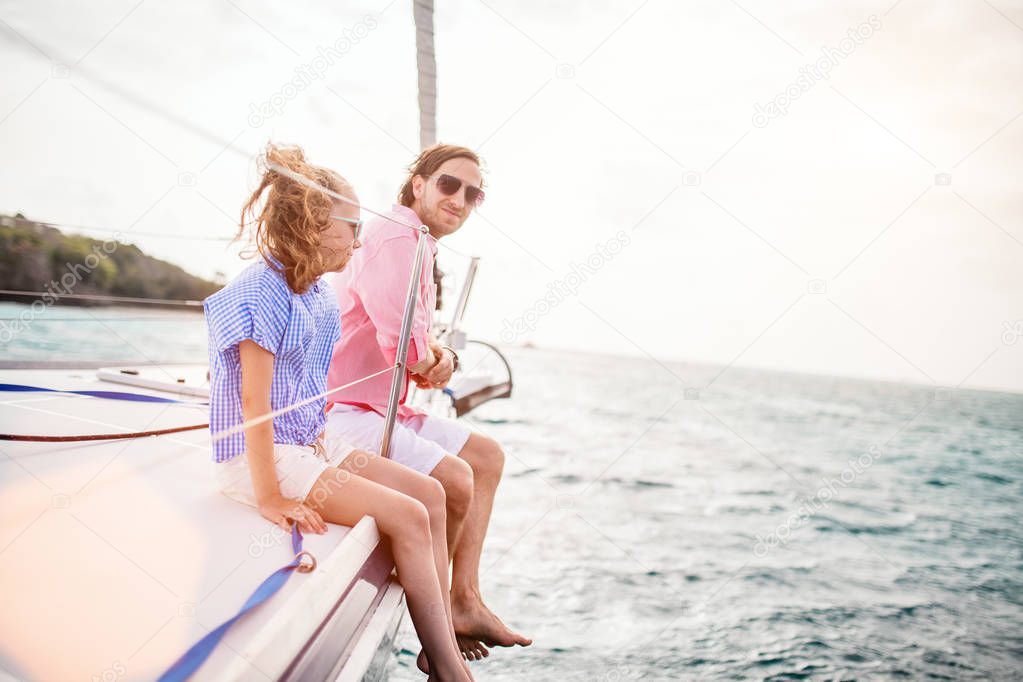 Father and daughter on board of sailing yacht enjoying sunset
