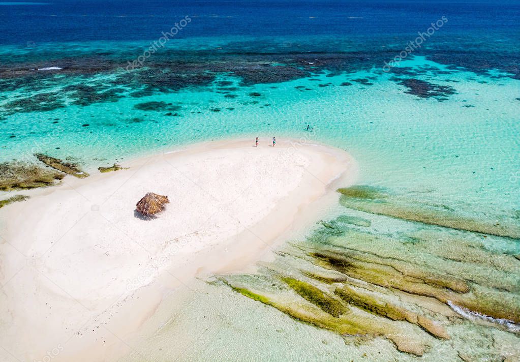 Aerial drone view of tiny tropical Mopion island sandbar, turquoise Caribbean sea and a family with kids in St Vincent and Grenadines