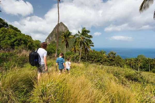 Family of father and kids hiking on summer day at tropical island of St Lucia in Caribbean with amazing views to iconic Pitons mountain