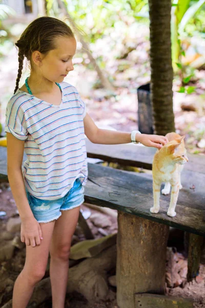 Little girl playing with cat outdoors