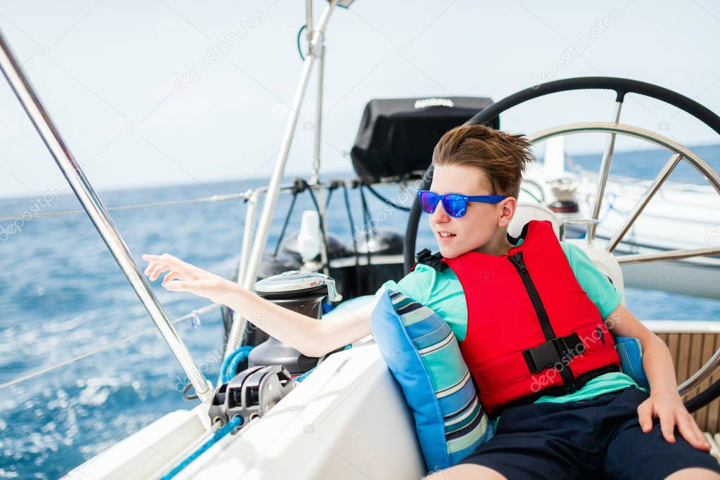 Teenage boy enjoying sailing on board a chartered catamaran or yacht