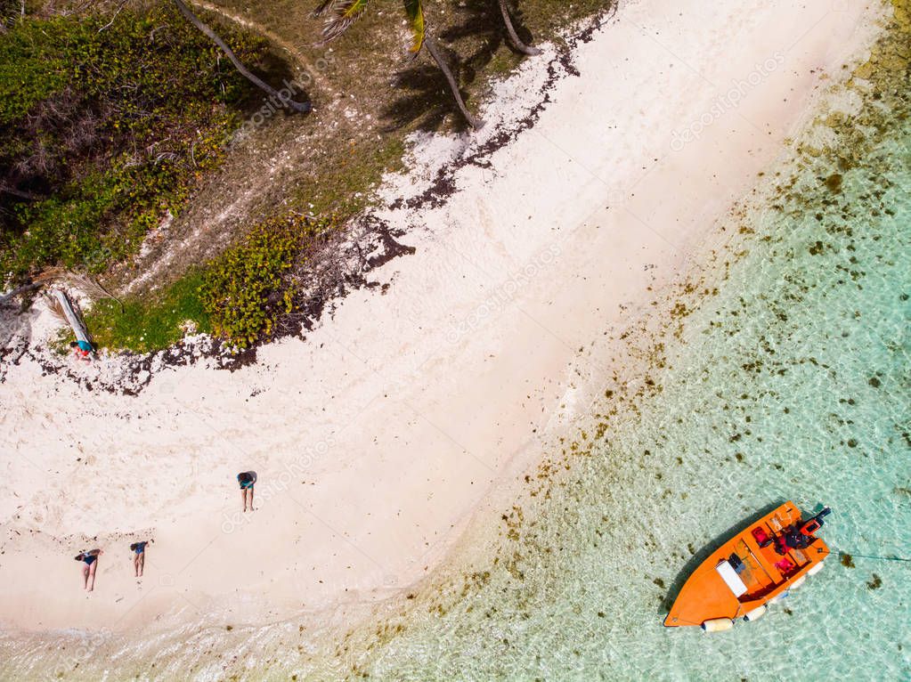 Aerial drone view of Petit Tabac tropical island, turquoise Caribbean sea of Tobago cays, and a family with kids in St Vincent and Grenadines