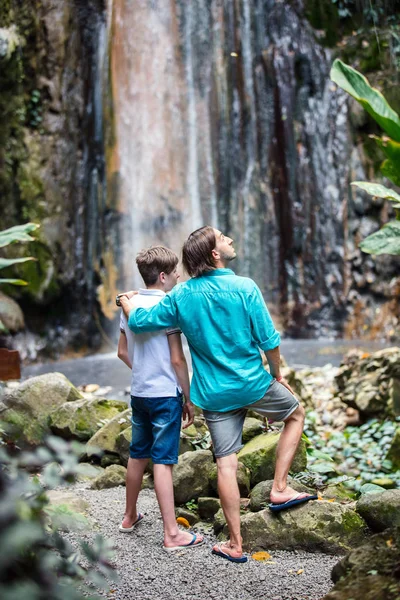 父と息子カリブ海セントルシア島のダイヤモンド滝の景色を楽しみながらのティーンエイ ジャーの背面図家族 — ストック写真