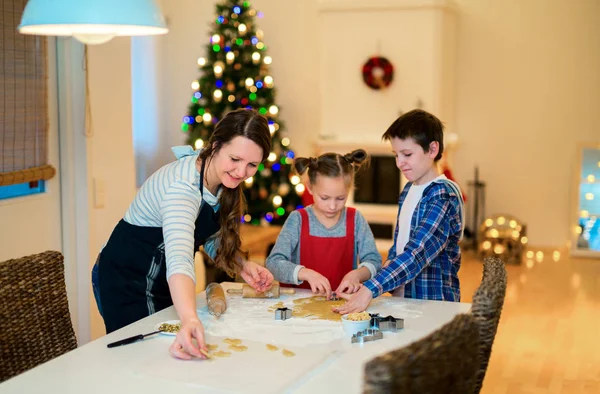 母亲和孩子在圣诞节前夜烘烤饼干在家的家庭 装饰精美的房间 圣诞树及背景灯 — 图库照片