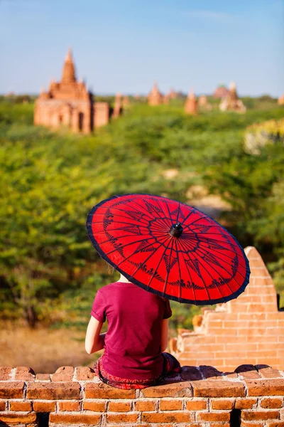 ミャンマー バガンの古代寺院の屋上の景色を楽しみながら伝統的なビルマの日傘を持つ少女の背面図 — ストック写真