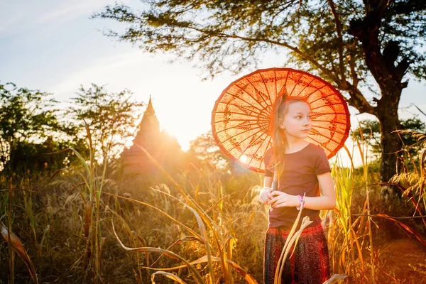 年轻女孩与传统缅甸阳伞参观在缅甸巴甘的古老寺庙在日落 — 图库照片