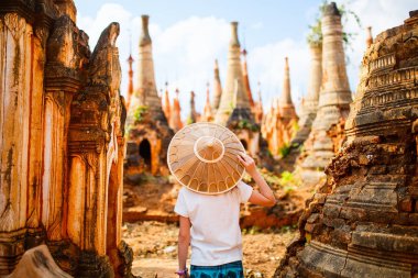 Young girl visiting hundrets of centuries old stupas in Indein near lake Inle in Myanmar clipart