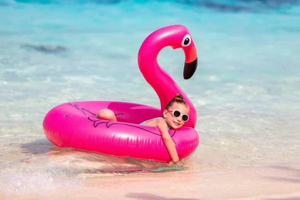 可爱的小女孩游泳在海洋中与充气粉红色火烈鸟戒指在暑假 — 图库照片